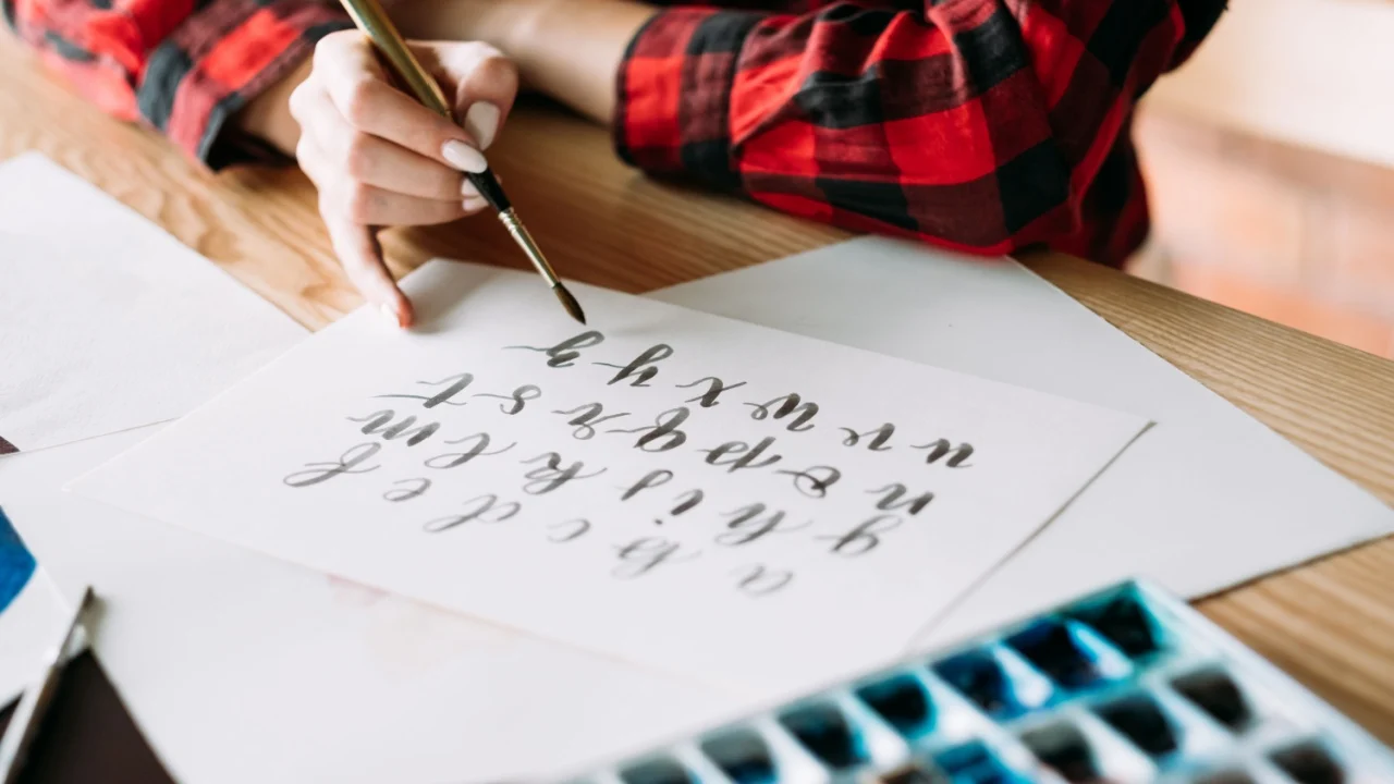 handwritten alphabet. woman mastering brush lettering craft and calligraphy art. artful hobby and creative leisure.