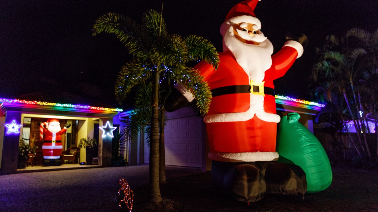 Big inflatable Santa Claus at CHRISTMAS LIGHTS festival in Queensland, Australia. House with Christmas characters and fairy lights in the evening. Australian suburbs. 
