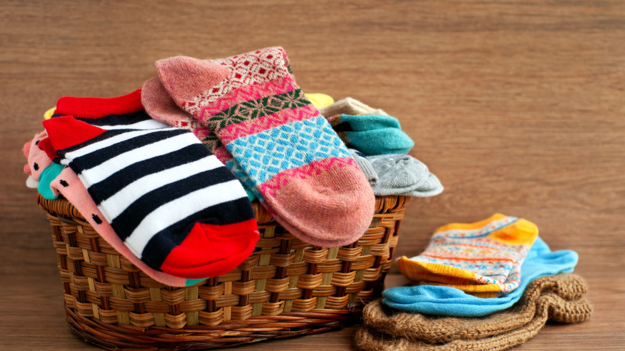 Basket with different socks. Socks of different sizes in a large wicker basket. Clothing for autumn and winter in the form of socks. A pile of colorful socks on a wooden background.