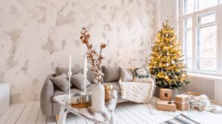 Light living room with Christmas tree. Comfortable sofa, high large Windows. Light white brick wall.