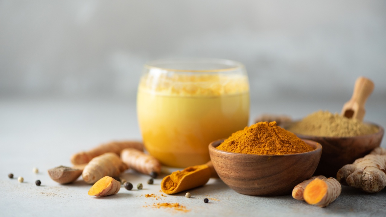 Healthy vegan turmeric latte or golden milk, turmeric root, ginger powder, black pepper over grey concrete background. Spices for ayurvedic treatment. Alternative medicine concept.