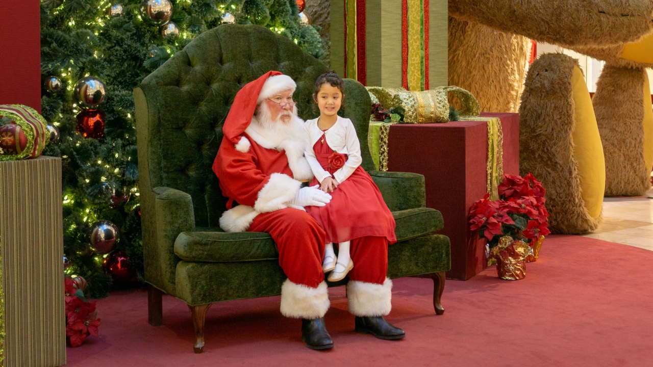Henderson, NV, USA - Dec 06-2018 - Santa Claus with a girl on his knee in front of a Christmas tree at the shopping mall Galleria at Sunset, Las Vegas.