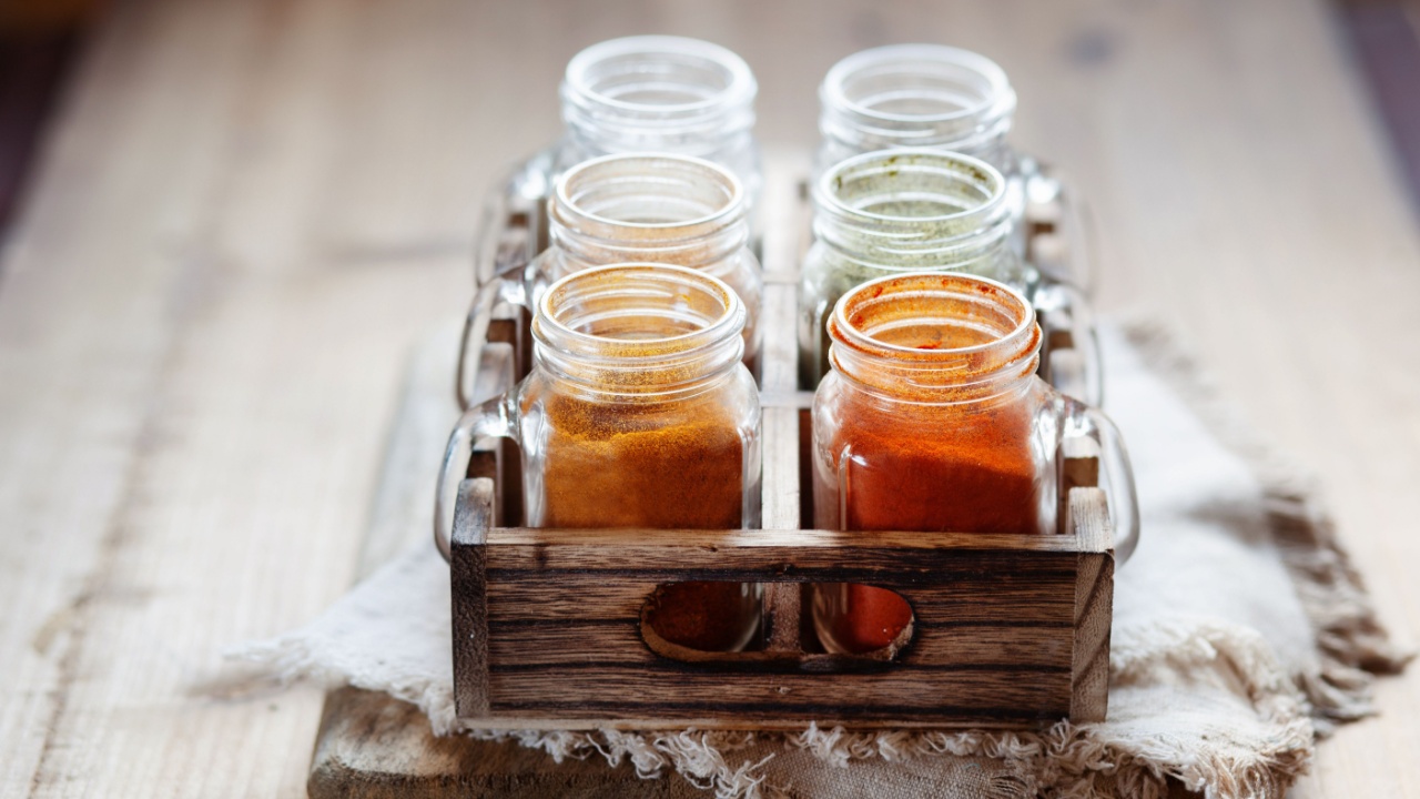 Spices and seasonings in glass jars on wooden container