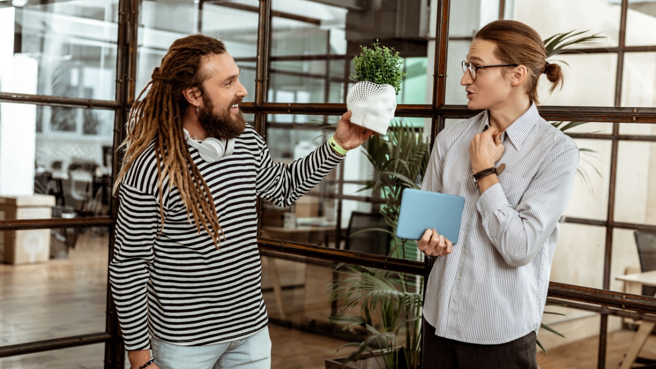 3d printing. Joyful bearded man standing with his colleague while showing him a skull model