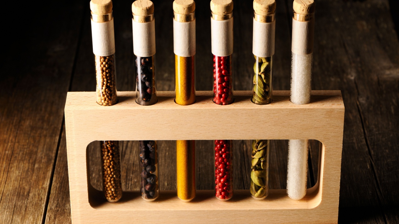 Spices in beakers on wooden table against dark background