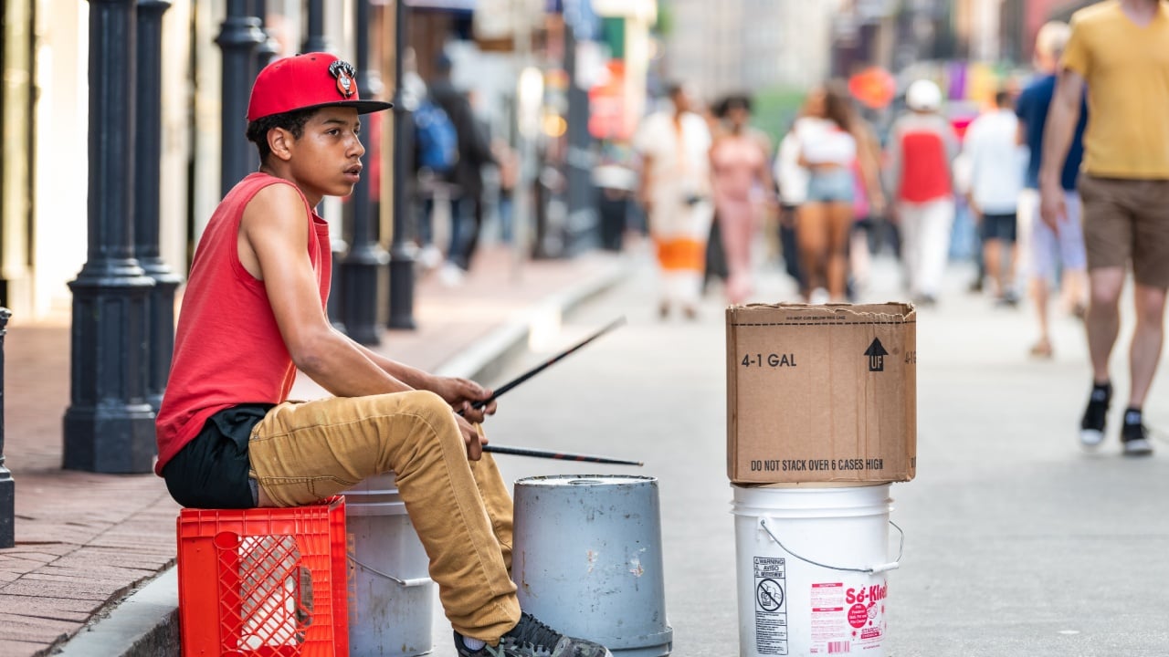 New Orleans, USA - April 23, 2018: Bourbon street in Louisiana famous city in evening young boy playing drums on buckets sidewalk