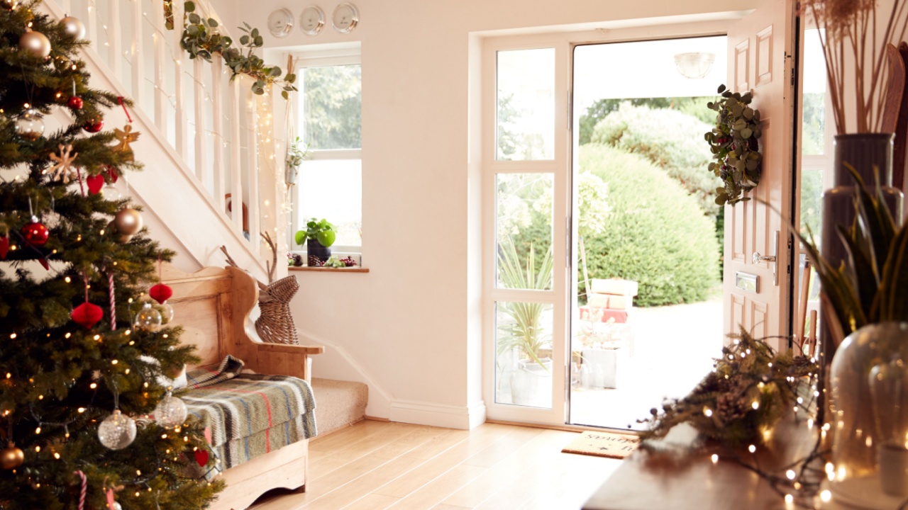 Hallway Of Home Decorated For Christmas Viewed Towards Open Front Door