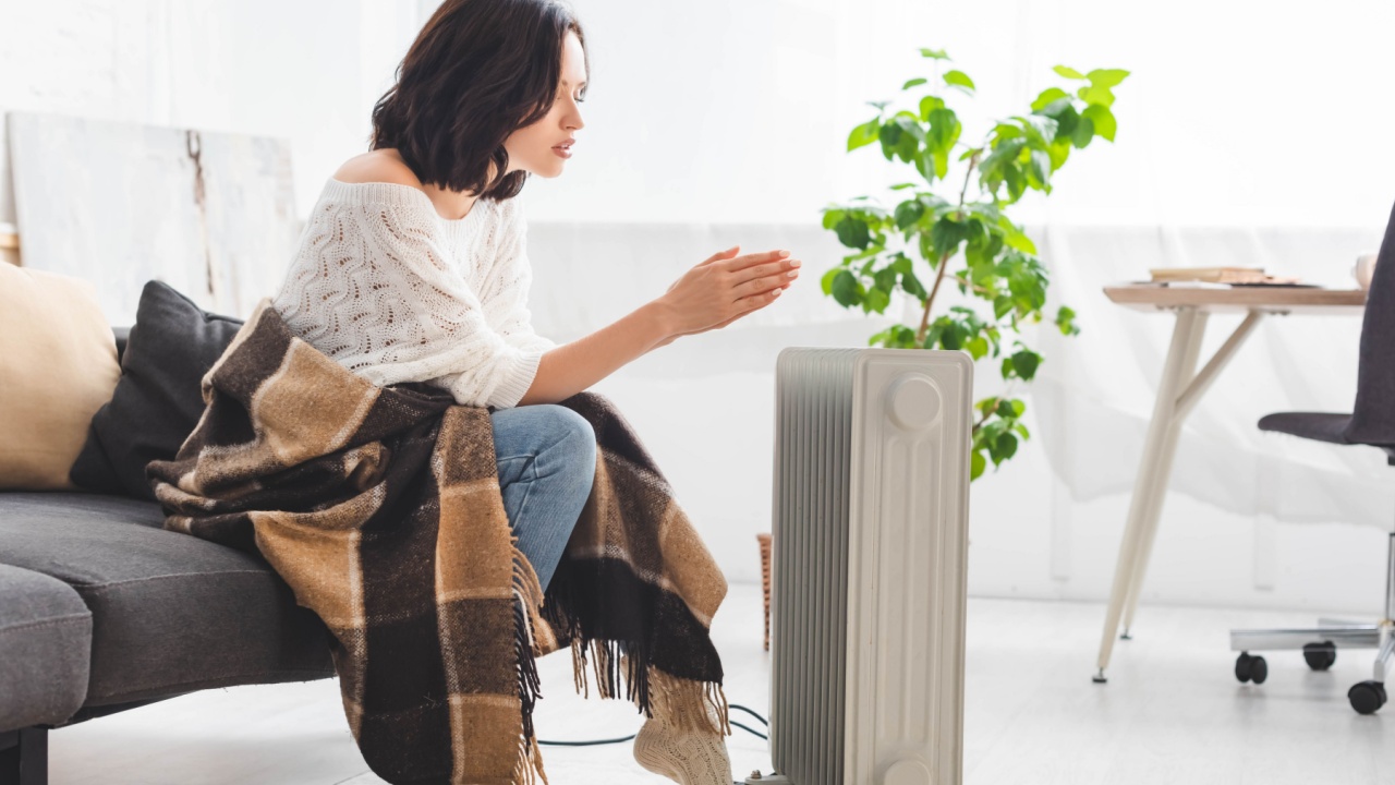 attractive young woman with blanket in cold room with heater