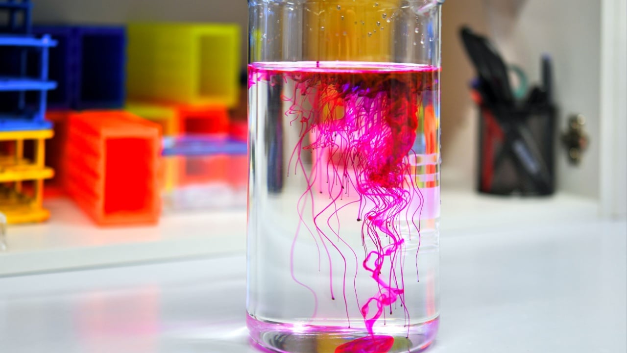 Dissolving of red fluorescent dye Rhodamine in beaker of water in chemical laboratory.