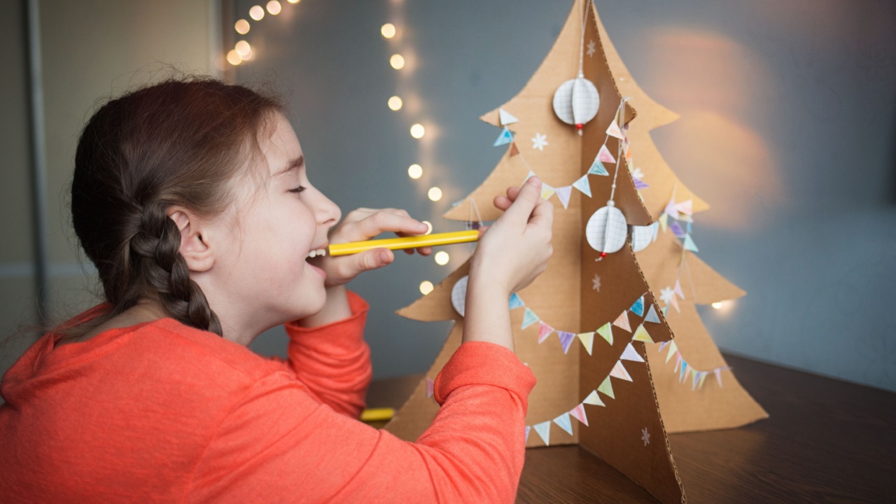 Christmas tree made of cardboard decorated with balls and garlands of flags. child makes crafts for the new year in school.