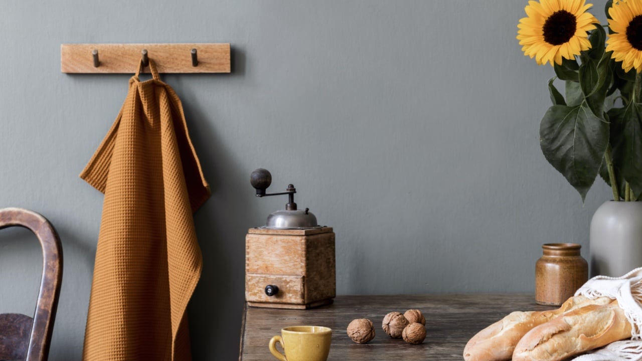 Vintage kitchen interior with wooden table, bag with bagels ,sunflowers in vase, cup of coffee and kitchen accessories. Minimalistic concept of kitchen space. Country side mood. Template.