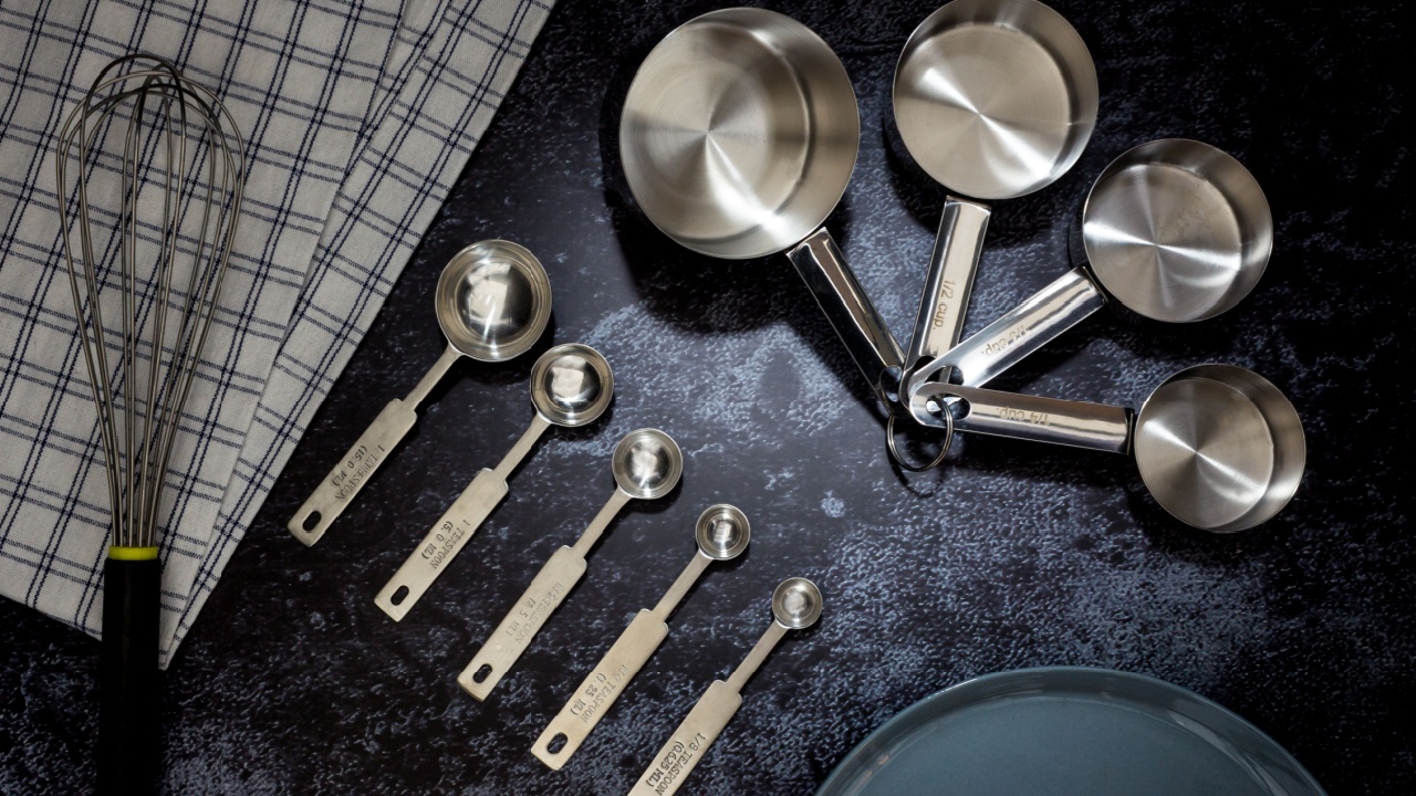 Collection of stainless measuring cups and measuring spoon with a plate in top view