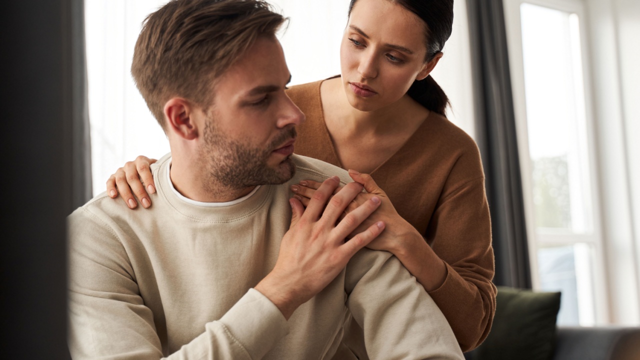 Caring caucasian wife caring and supporting to her upset husband. Unshaven man suffering and feeling down, supportive woman hugging spouse while showing empathy