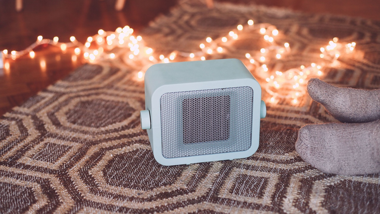 A blue retro heater on the floor, feet in socks and cosy Christmas lights