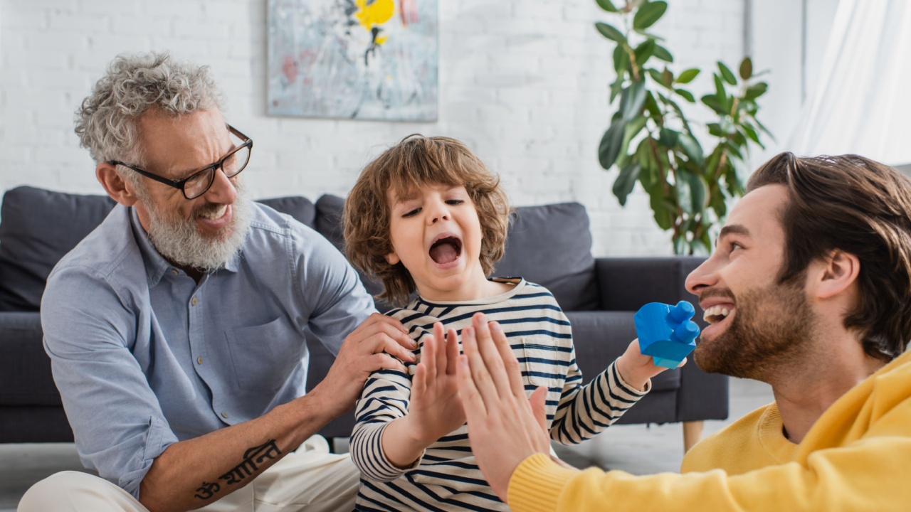 Smiling father and son with building blocks giving high five near grandfather