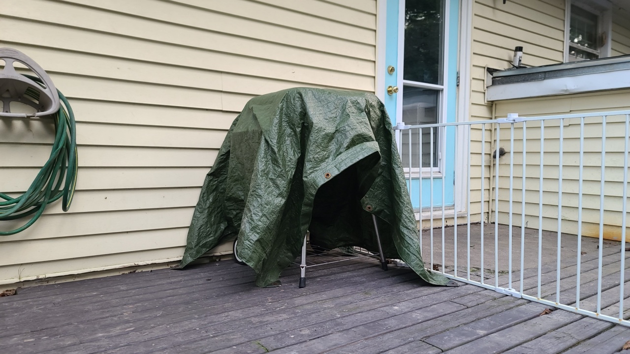 A covered barbeque sitting against the wall on a wooden deck in a suburban home.