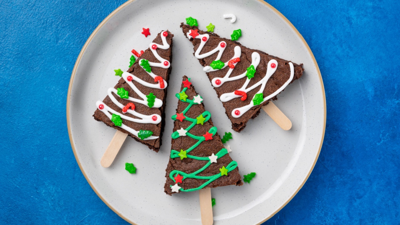 Christmas chocolate brownies with sugar glaze and sprinkles on a blue concrete background. Christmas or New Year food festive background.Top view, copy space