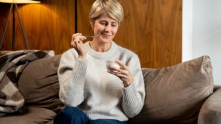 Portrait of a middle-aged woman who eats yogurt sitting on the couch at home