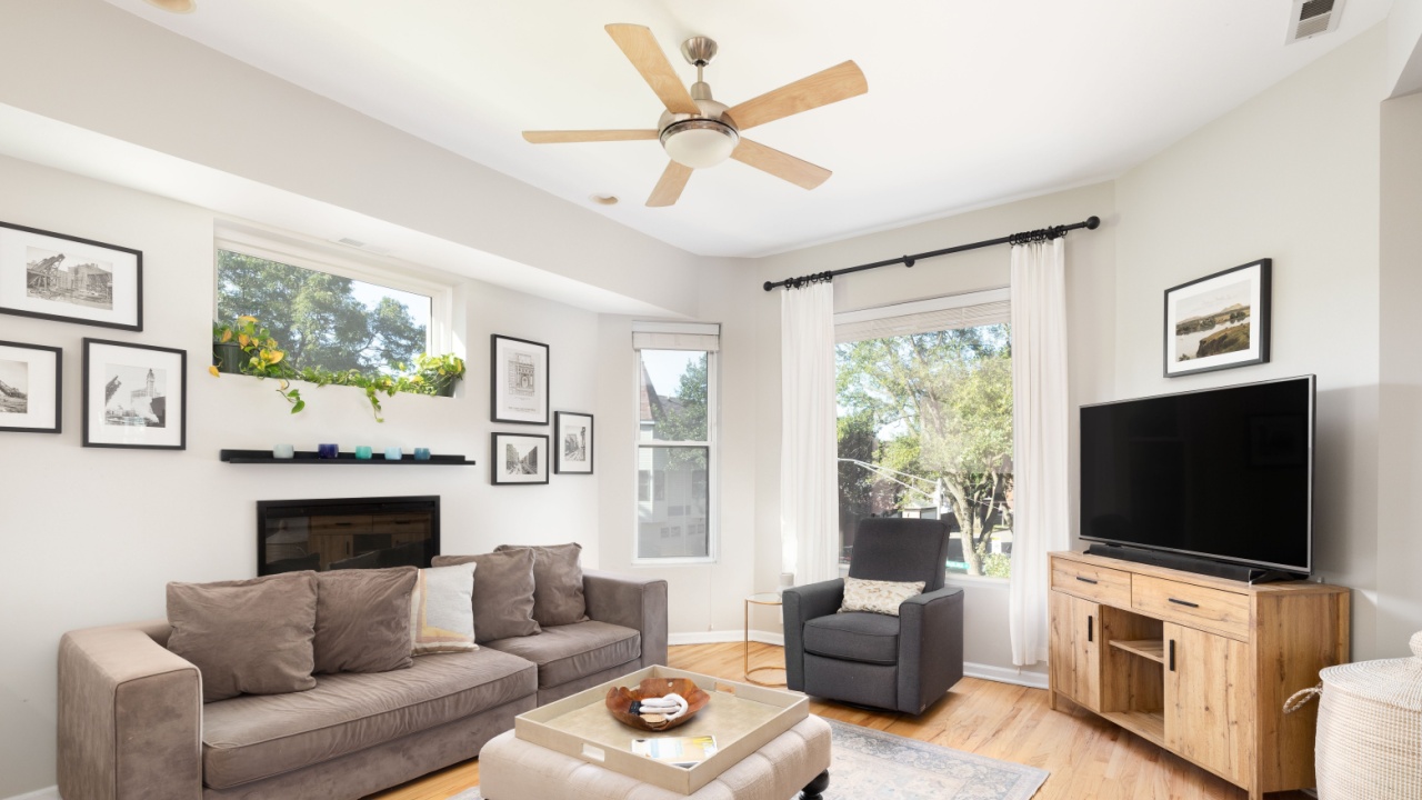 CHICAGO, IL, USA - SEPTEMBER 4, 2021: A bright living room with a couch and chair sitting on hardwood floors in front of a television.