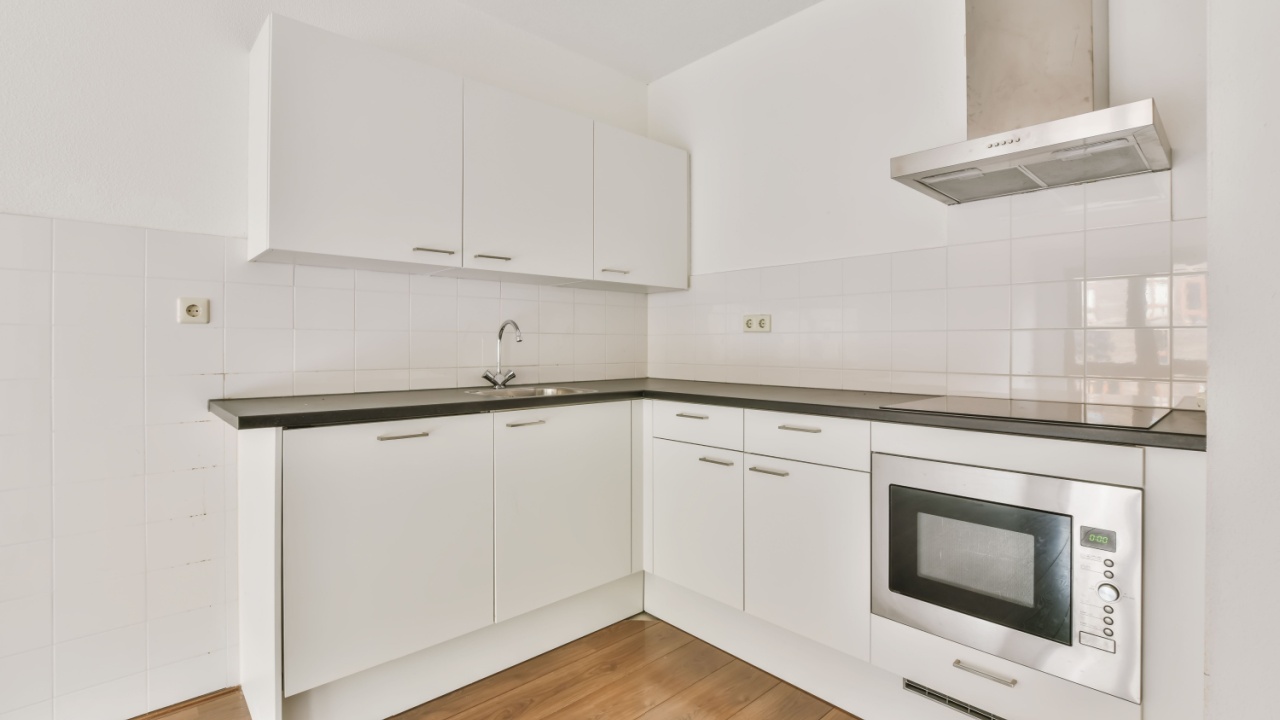 Luxurious small kitchen with white kitchen unit and delightful parquet flooring