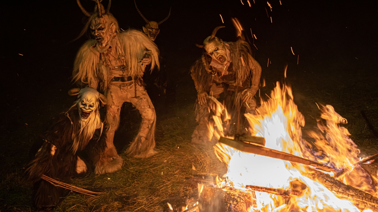 TARVISI, ITALY - Dec 05, 2018: A Man masked with a spooky Krampus character costume and fire in the background holidays concept
