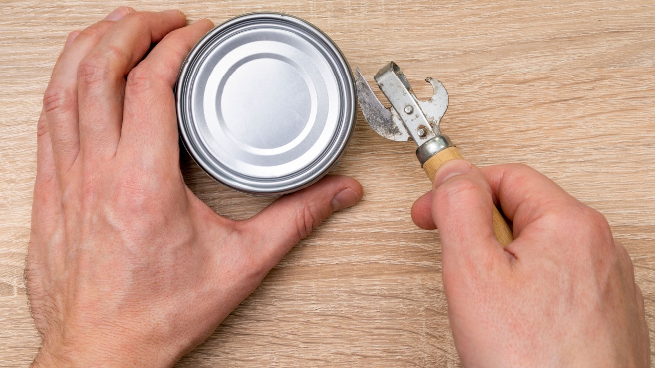 Man opening a can with a can opener. Canned food.