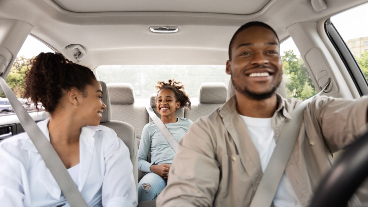 Joyful Black Family Driving New Car Having Ride In City. Parents And Daughter Sitting In Automobile Enjoying Road Trip On Vacation. Transportation Concept. Selective Focus