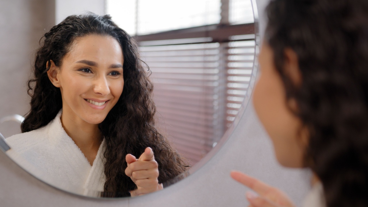 Young happy confident woman standing in bathroom looking in mirror rehearsing speech instructs preparing for interview says inspiring words motivates to win winks at reflection morning routine
