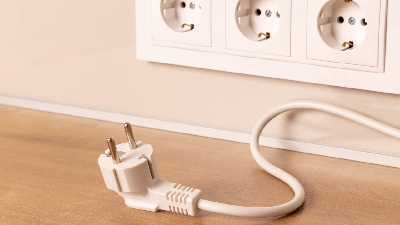 Power cord cable unplugged with group of white european electrical outlets on modern beige wall