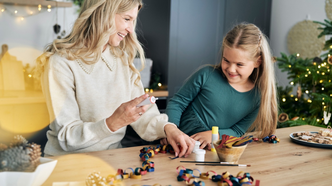 Caucasian girl and mother preparing DIY paper chain for Christmas tree and talking