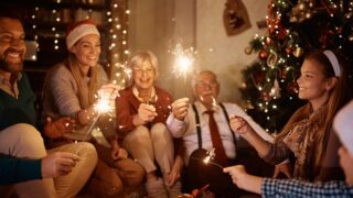 Cheerful extended family having fun with sparklers while celebrating Christmas together at home.