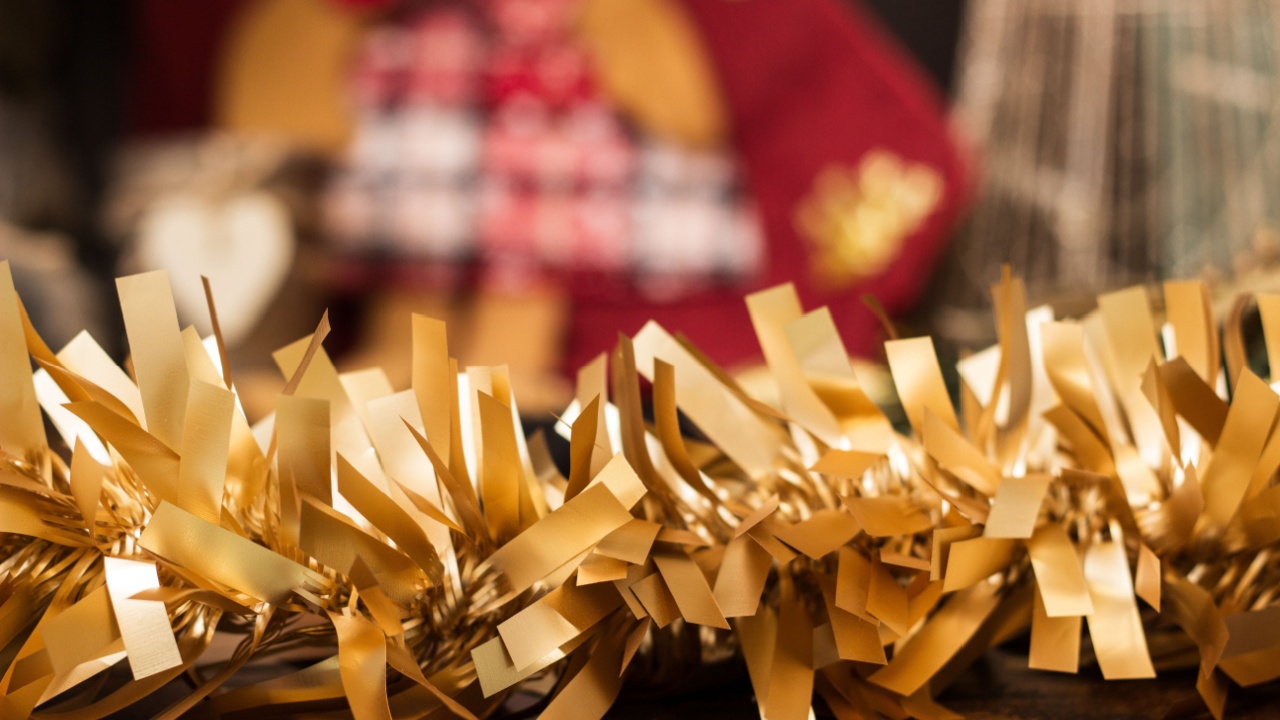 Christmas gold tree tinsel background. In the background a defocused Christmas stocking and tree