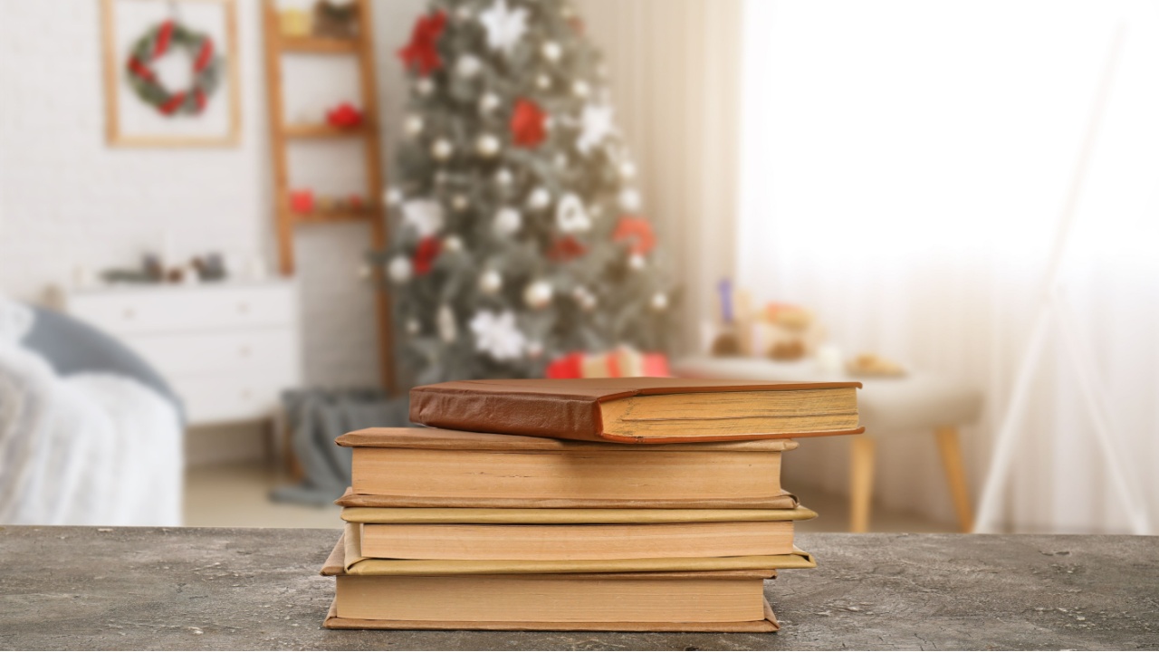 Old books on table in room decorated for Christmas