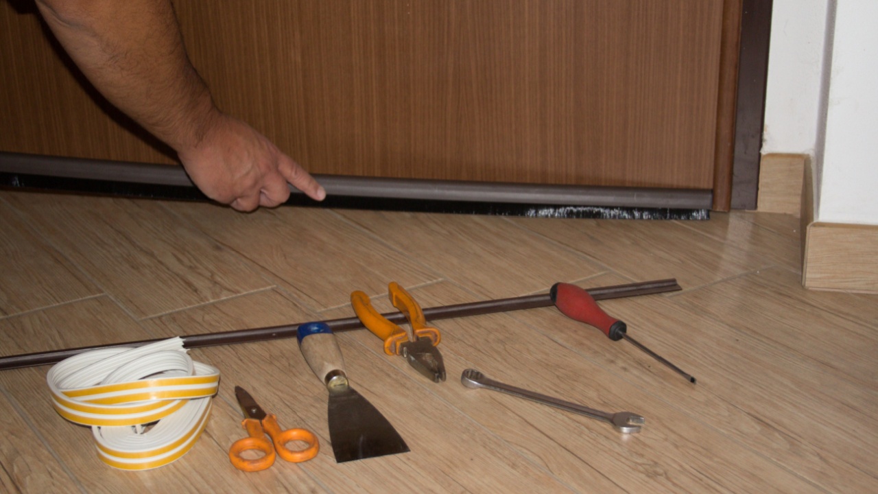 Handyman installing a dust seal on the house door. Better thermal insulation and cleaning of the floor. Horizontal banner
