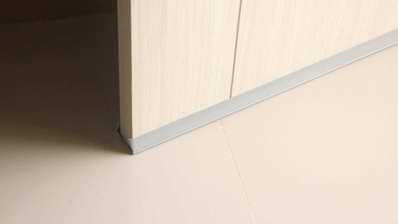 Grey door bottom seal for anti dust and insect. Water flood prevention. Waterproof rubber material object. Penghalang bawah pintu. Isolated house door equipment photo on ceramic flooring.