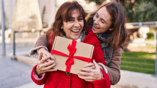 yougng woman giving her mom, women, gardener, a gift with a red bow hug