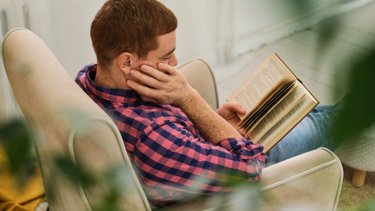 Nature's Reading Nook. Man enjoying a tranquil reading moment at home, enveloped by vibrant green leaves.