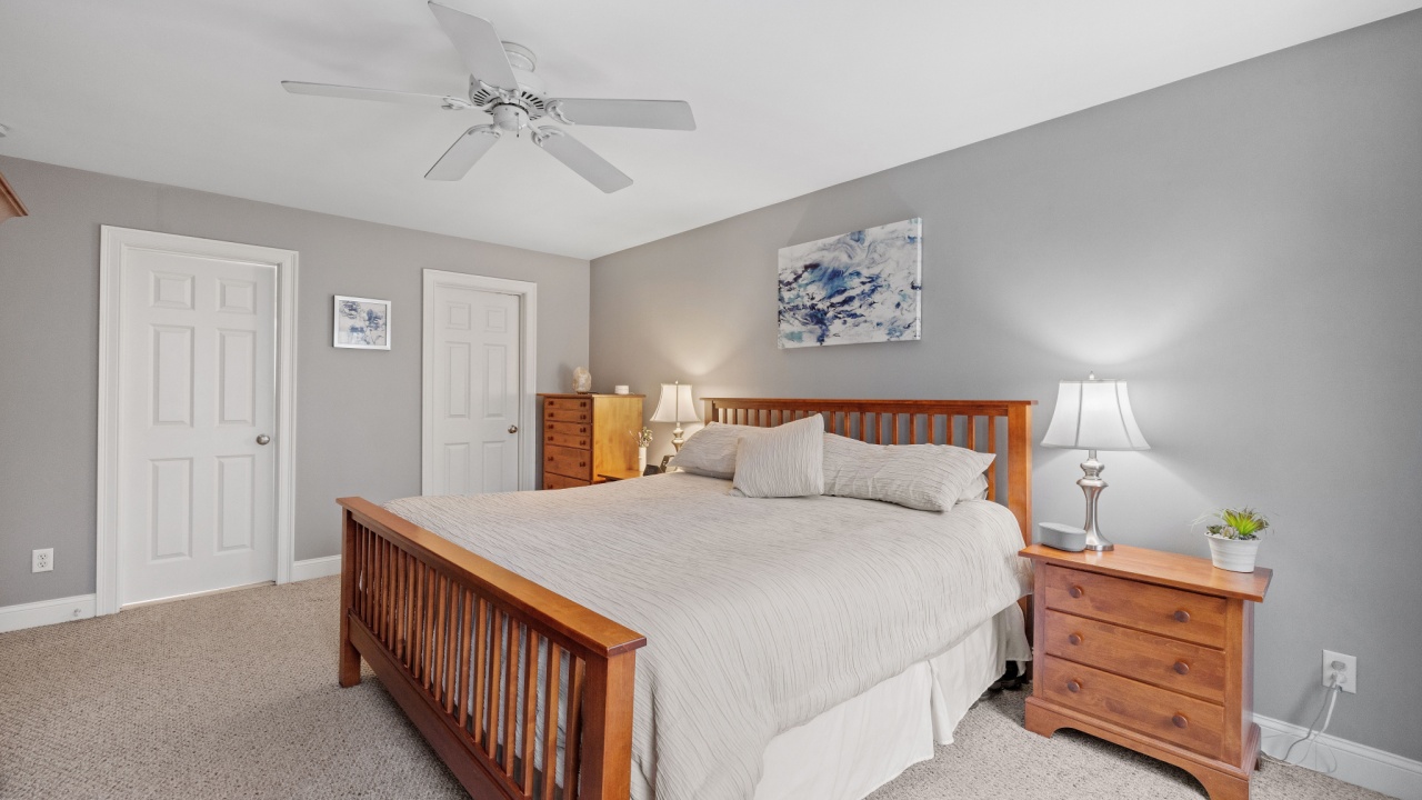 A cozy bedroom interior, furnished with a single bed, dresser and ceiling fan