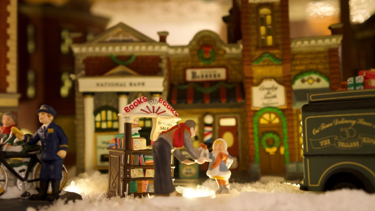 miniature book shop in miniature christmas town. Man giving books to girl in snowy village. Traditional american miniature christmas decoration for the holidays.