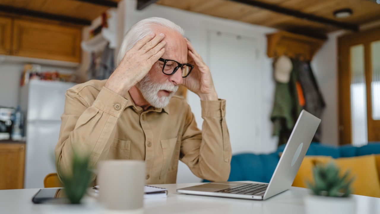 One senior caucasian man grandfather with beard and eyeglasses work on laptop use computer at home solving problem worried frustration