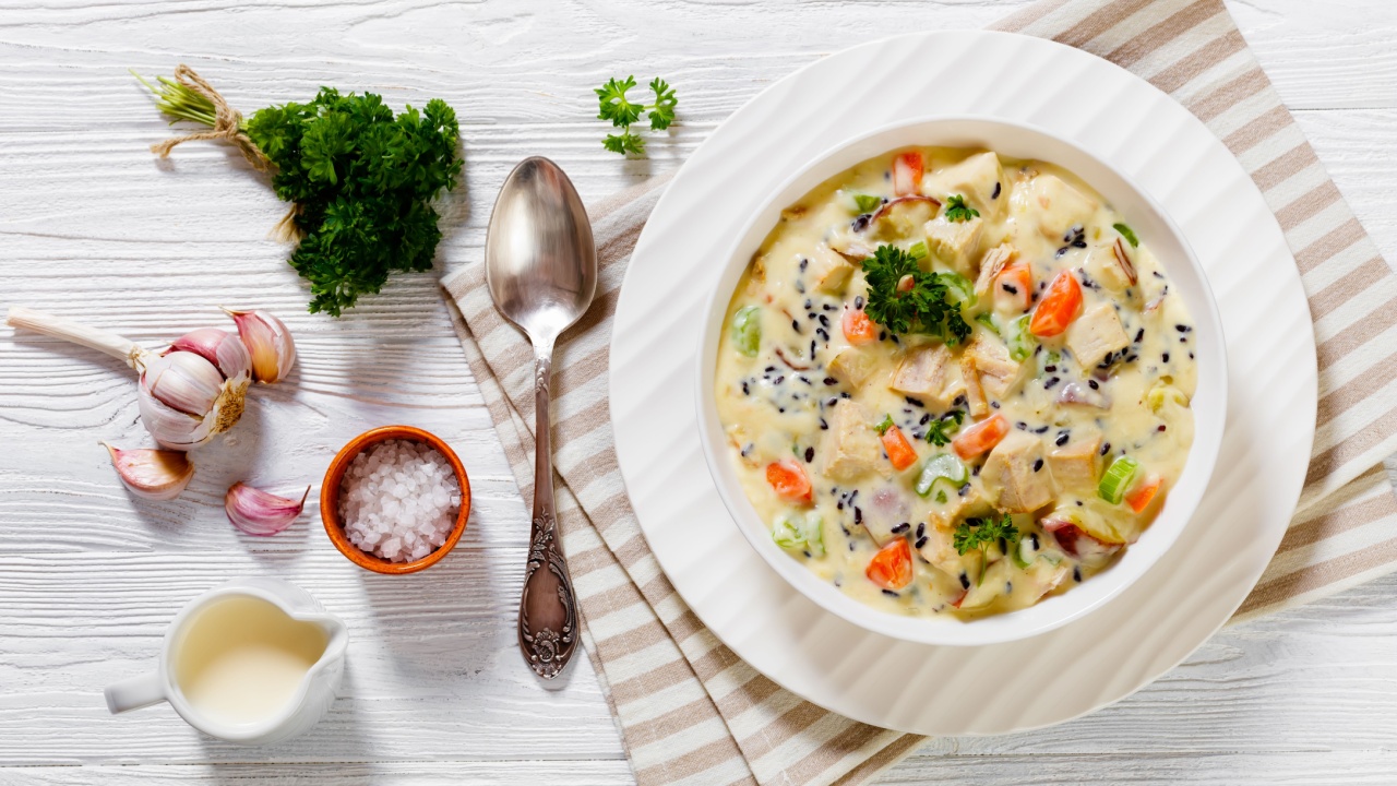 Turkey Wild Rice Creamy Soup with red potatoes. carrot, celery, spices and herbs in white bowl on wooden table with spoon, flat lay