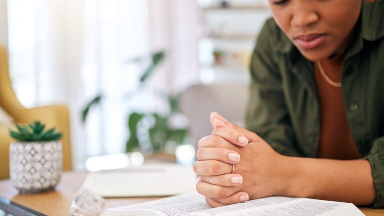 Woman, bible and prayer in home, desk and mindfulness for faith, religion and reading with hope for future. African lady, praying hands and study holy book for peace, mental health or worship to God