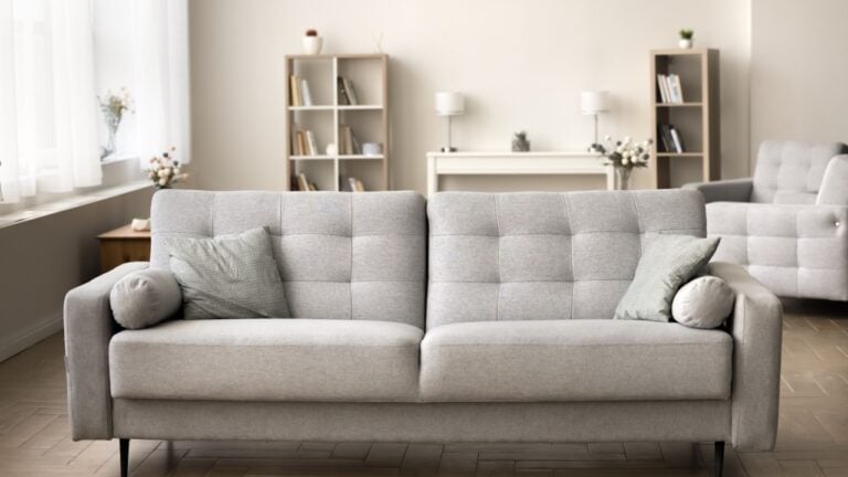 Comfortable grey couch in cozy empty living room. Modern Scandinavian interior with stylish sofa, cushions, cozy home decoration, elegant furniture in background. Real estate apartment for rent, sale