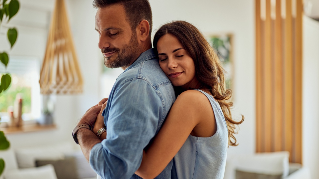 A couple in love enjoying a hug in the morning at home, feeling peaceful.