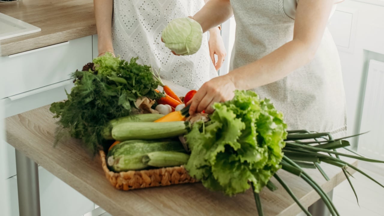 A woman puts various vegetables on the kitchen table for preparing dietary food. Diet food.