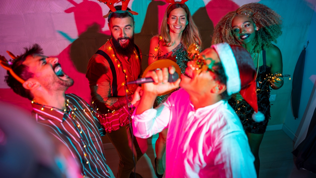 Group of cheerful young friends having fun singing karaoke and dancing at New Year Eve party