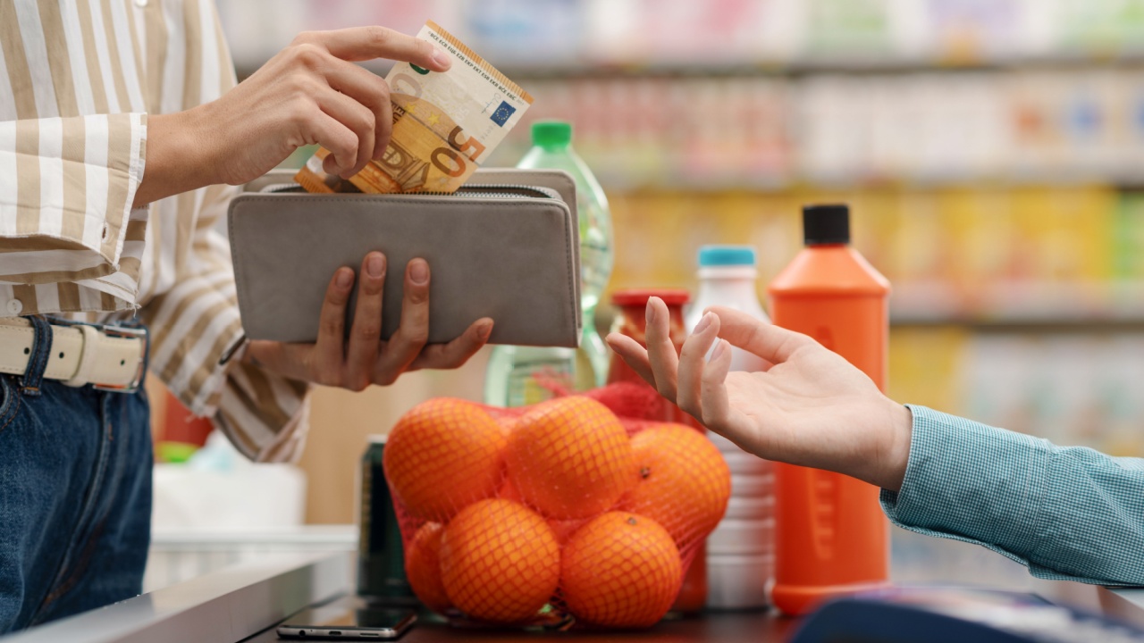 Woman paying for her groceries at the supermarket checkout, she is giving cash money to the cashier