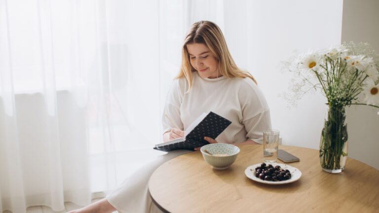 Young beautiful female student at home doing creative journal.