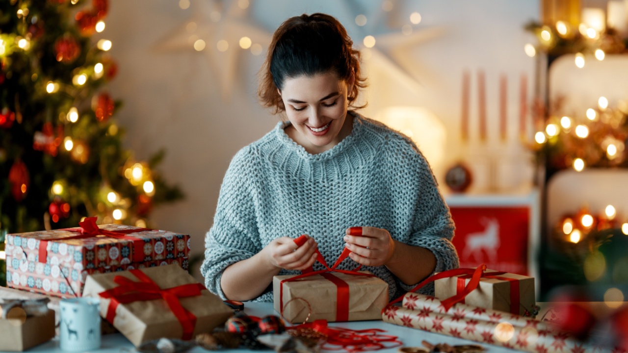 Merry Christmas and Happy Holidays. Cheerful pretty young woman preparing presents.