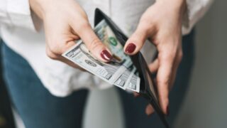 Woman's hands taking out money from wallet, dollar banknote cash.